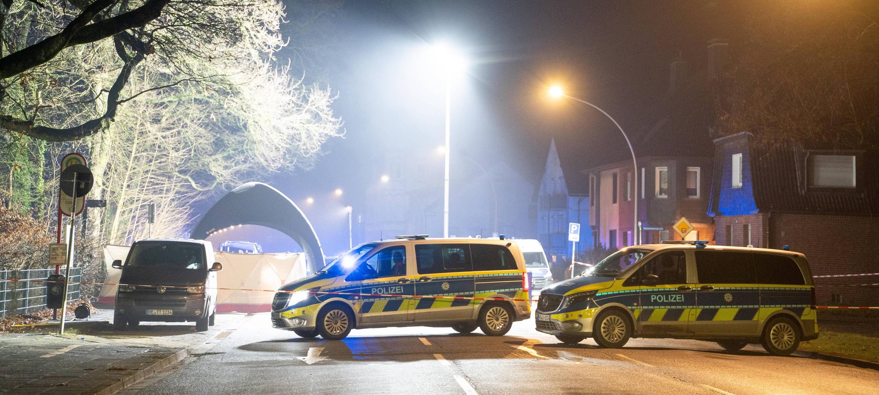 Polizeiautos stehen vor einer ausgeleuchteten Straße am Tatort