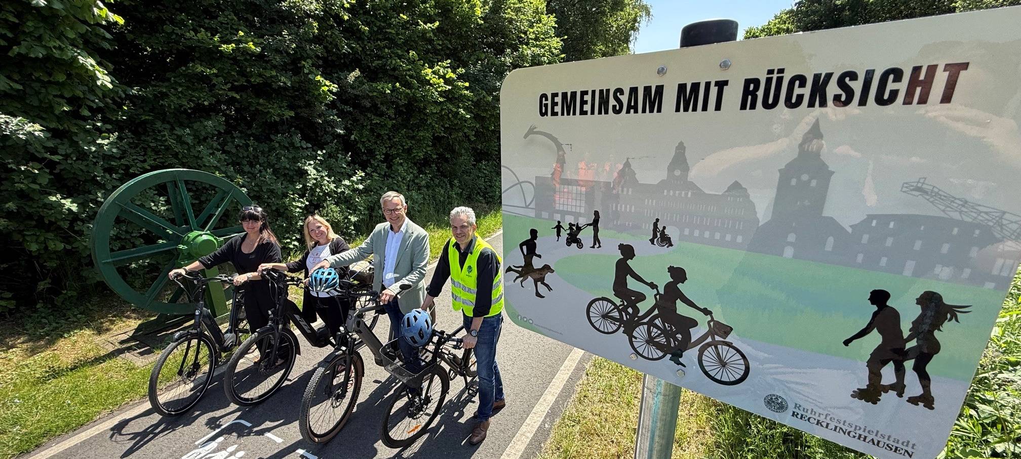 Vier Fahrradfahrer stehen in Recklinghausen neben einem Schild mit der Aufschrift "Gemeinsam mit Rücksicht"